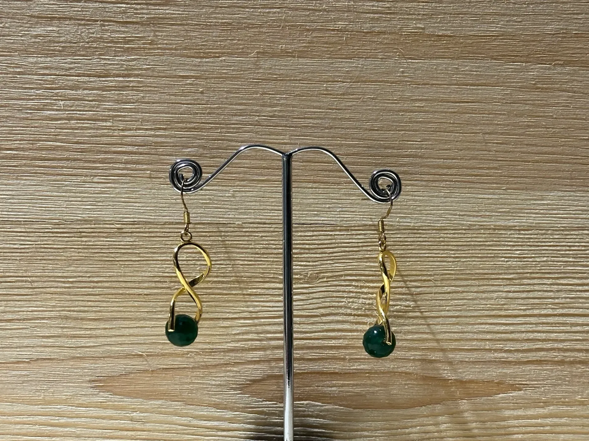 Boucle d'oreille dorée torsadée avec perle verte