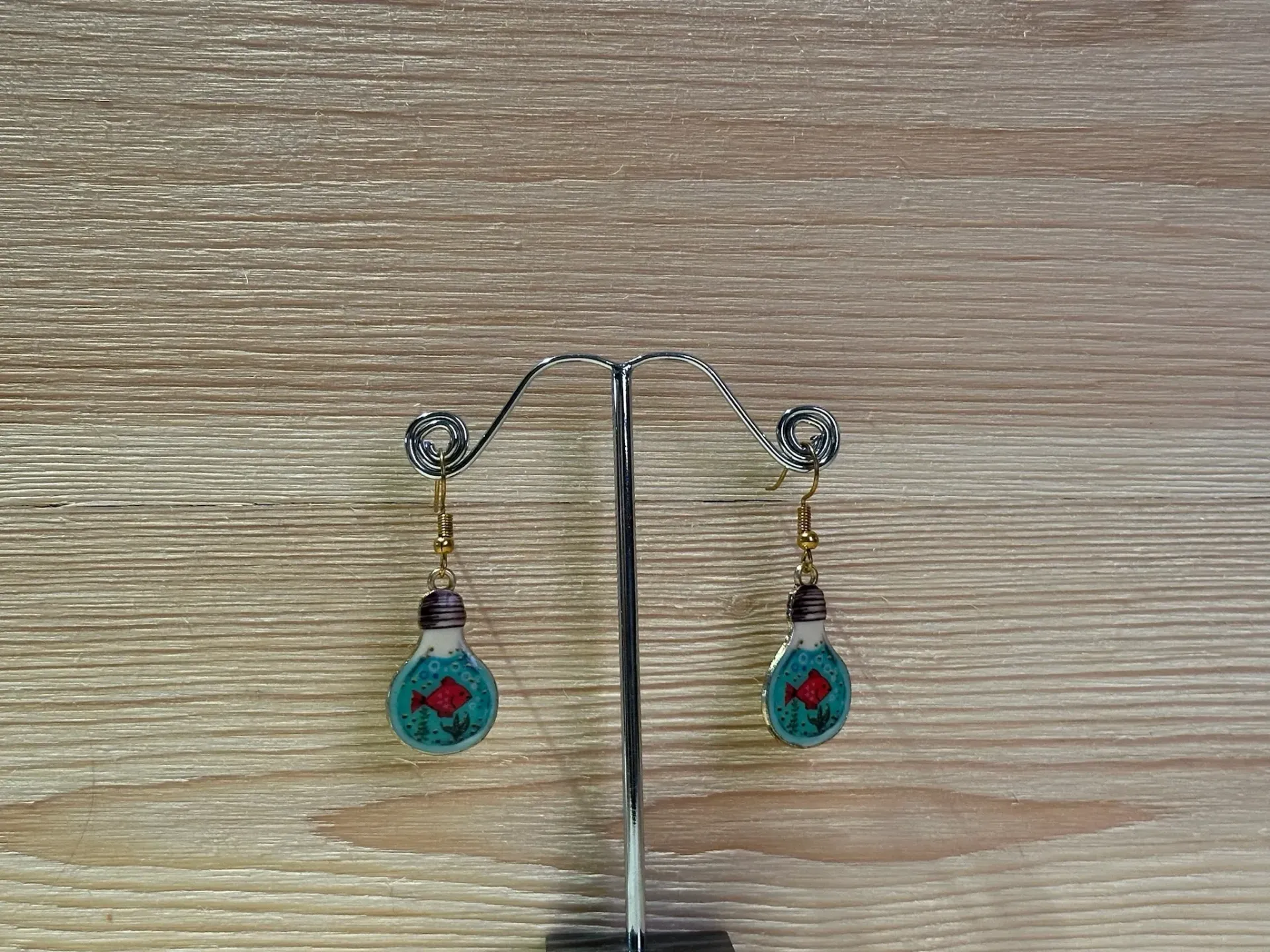 Boucle d'oreilles dorées en forme d'ampoule avec un petit poisson dedans en acier inoxydable